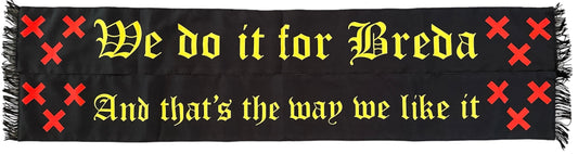 Deze foto toont een zwarte NAC Breda sjaal met de tekst "We do it for Breda" en "And that's the way we like it" in gele gotische letters. De sjaal is versierd met rode Andreaskruisen, een symbool van Breda. Deze sjaal is een perfecte manier om je steun te tonen aan NAC Breda en je verbondenheid met de stad Breda te uiten. Ideaal voor wedstrijden, sfeeracties en dagelijks gebruik.