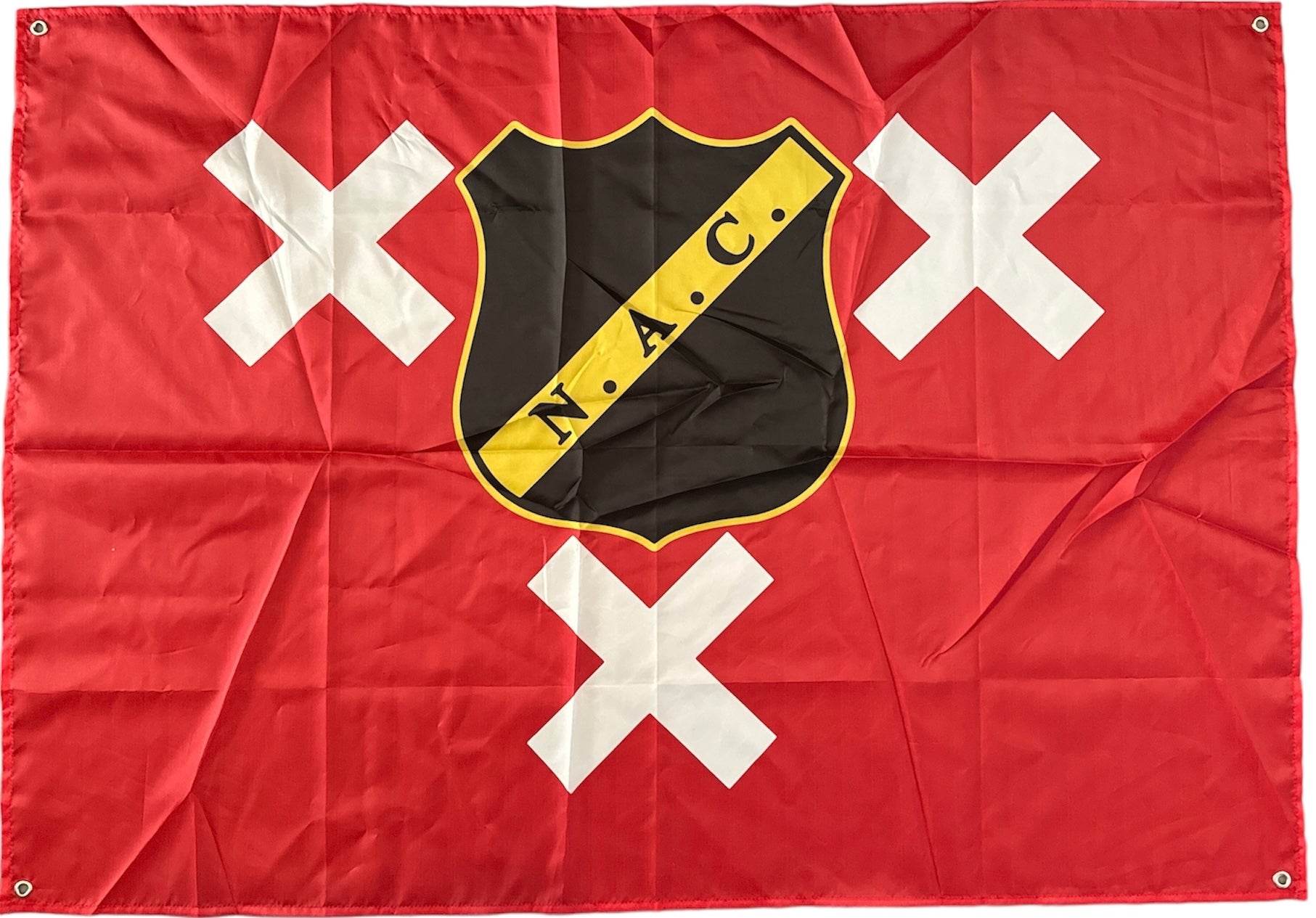 Deze foto toont een rode NAC Breda vlag met witte Andreaskruisen en het iconische NAC clublogo in het midden. De Andreaskruisen zijn een symbool van Breda en benadrukken de sterke band tussen de club en de stad. Deze vlag is een perfecte manier om je steun te tonen aan NAC Breda en je verbondenheid met de stad Breda te uiten. Ideaal voor wedstrijden, sfeeracties en als decoratie.