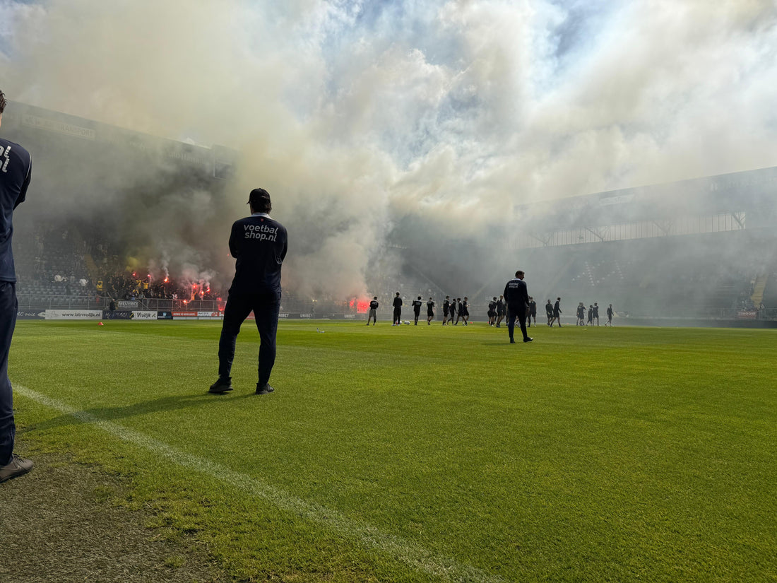 Trainer Carl Hoefkens kijkt naar de B-side tijdens de laatste training voor de derby. De tribune is gevuld met rook van fakkels.