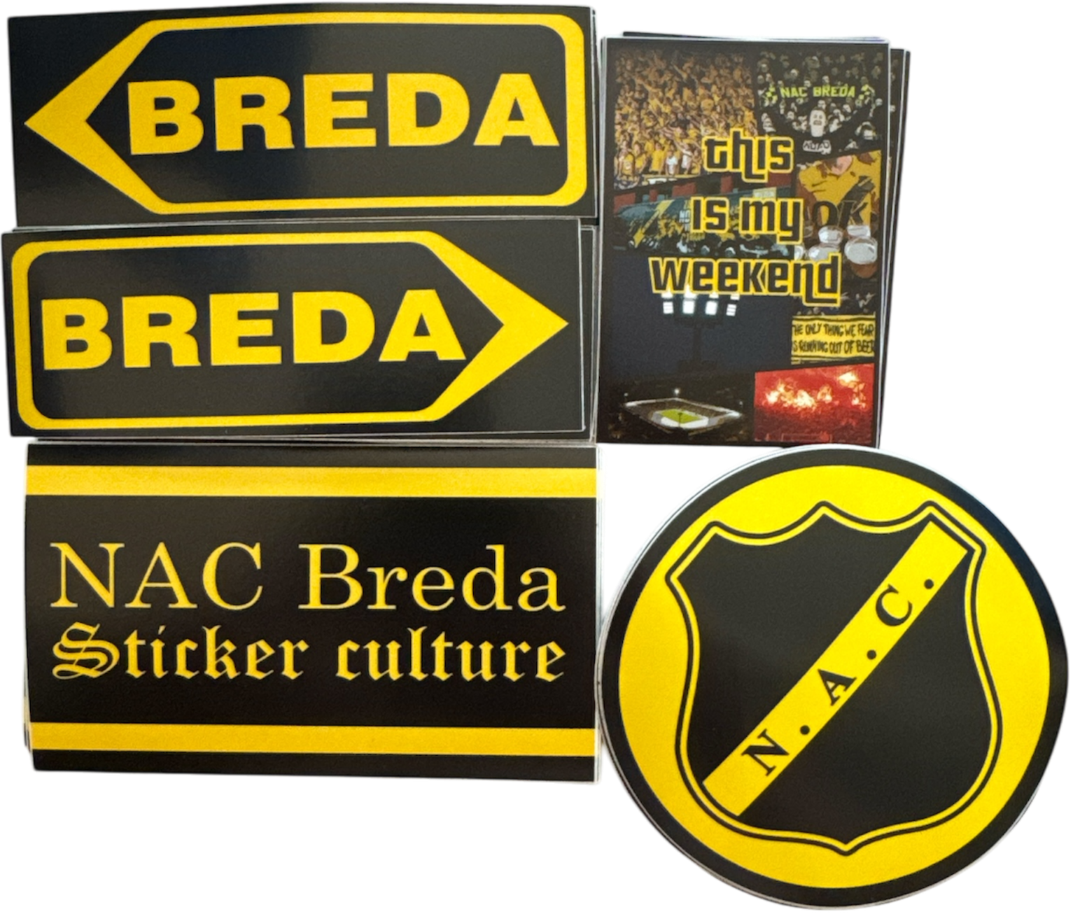  Een verzameling stickers en een boekje gerelateerd aan NAC Breda, een voetbalclub. De items omvatten:

Twee rechthoekige stickers met het woord "BREDA" in gele tekst op een zwarte achtergrond.
Een pijlvormige sticker met het woord "BREDA" in gele tekst op een zwarte achtergrond.
Een rechthoekige sticker met de tekst "NAC Breda Sticker culture" in gele tekst op een zwarte achtergrond.