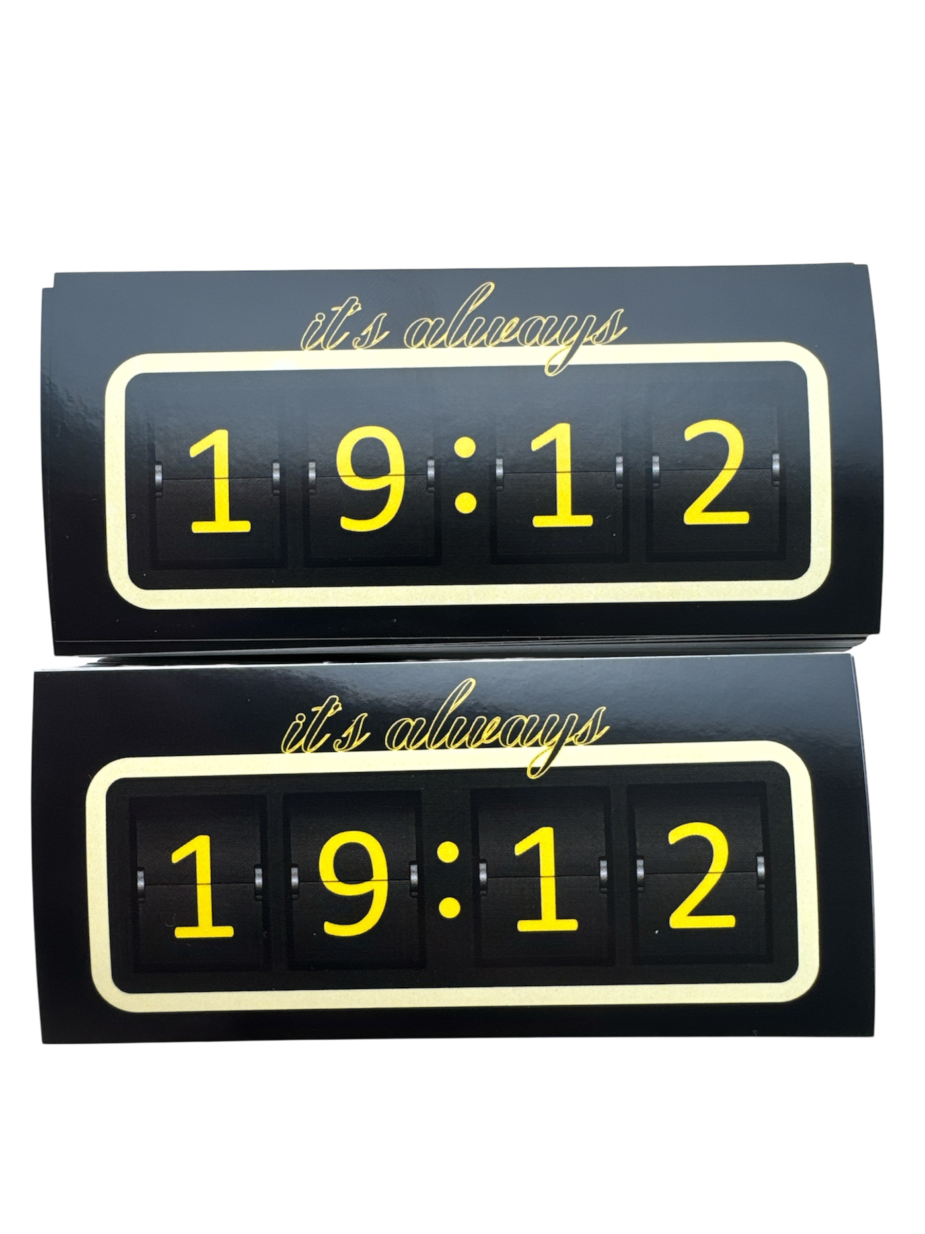 wee identieke rechthoekige stickers met een zwart design en een gele rand. De stickers tonen de tekst 'it's always' in script lettertype bovenaan, en daaronder de cijfers '19:12' in een digitaal klokstijl lettertype, gescheiden door stippen.