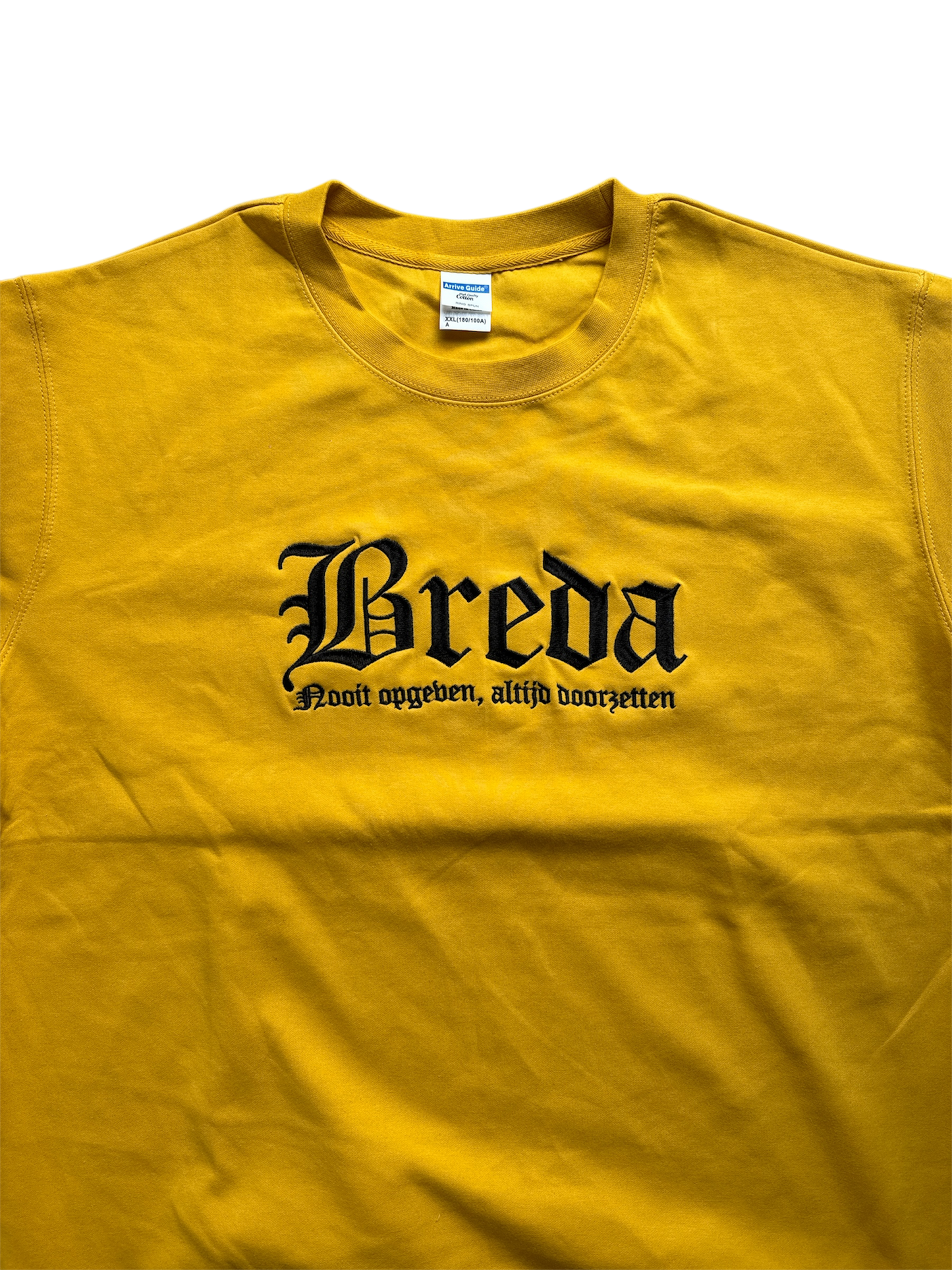 Gele NAC Breda sweater met zwart geborduurde tekst 'Breda' in gotisch lettertype en daaronder de slogan 'Nooit opgeven, altijd doorzetten'