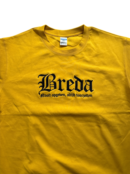 Gele NAC Breda sweater met zwart geborduurde tekst 'Breda' in gotisch lettertype en daaronder de slogan 'Nooit opgeven, altijd doorzetten'