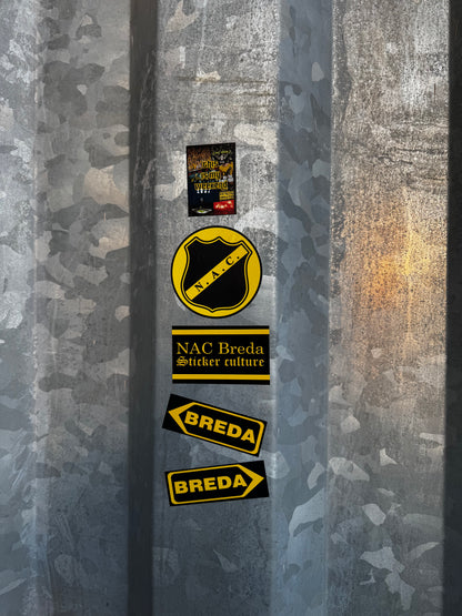 NAC Breda stickers uit pakket 1, waaronder het officiële logo en Breda richtingaanwijzers, aangebracht op de ruwe, gegalvaniseerde hekken van het NAC stadion.