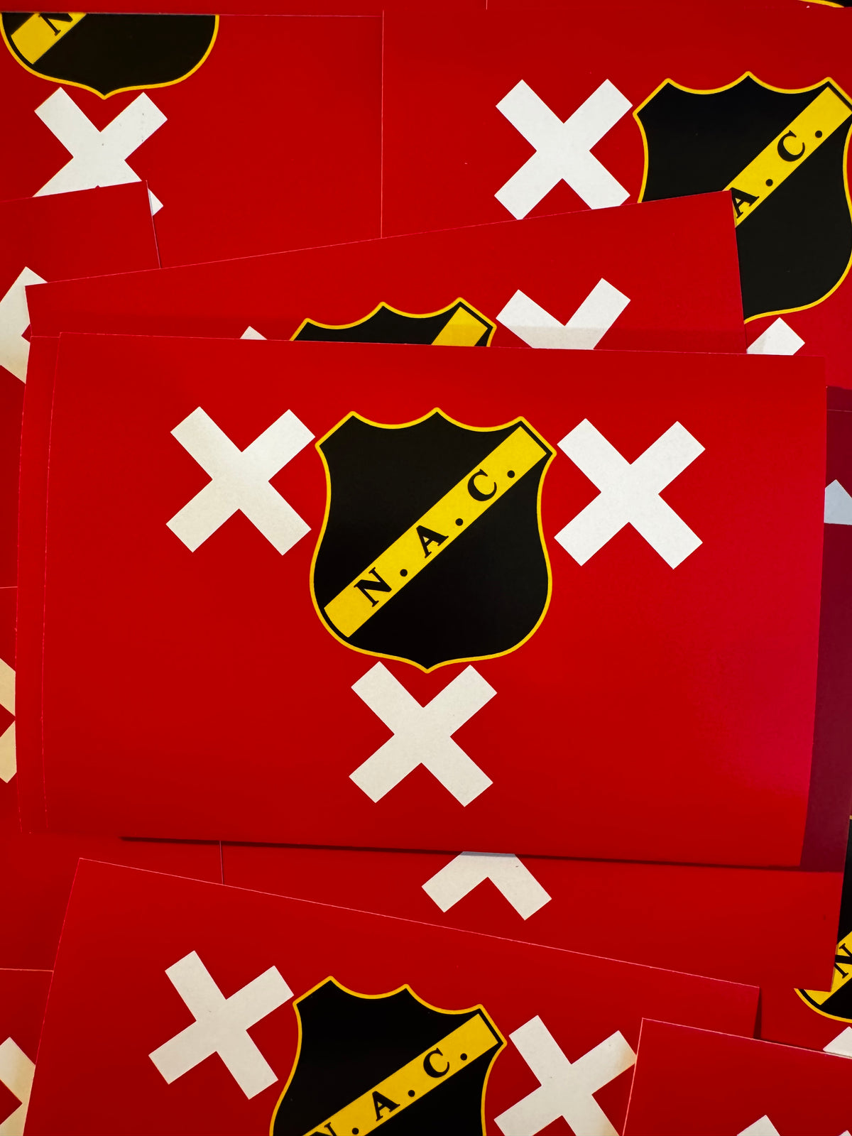 NAC Breda stickers van bovenaf, rode Breda-vlag met witte kruizen en het geel-zwarte NAC-schild