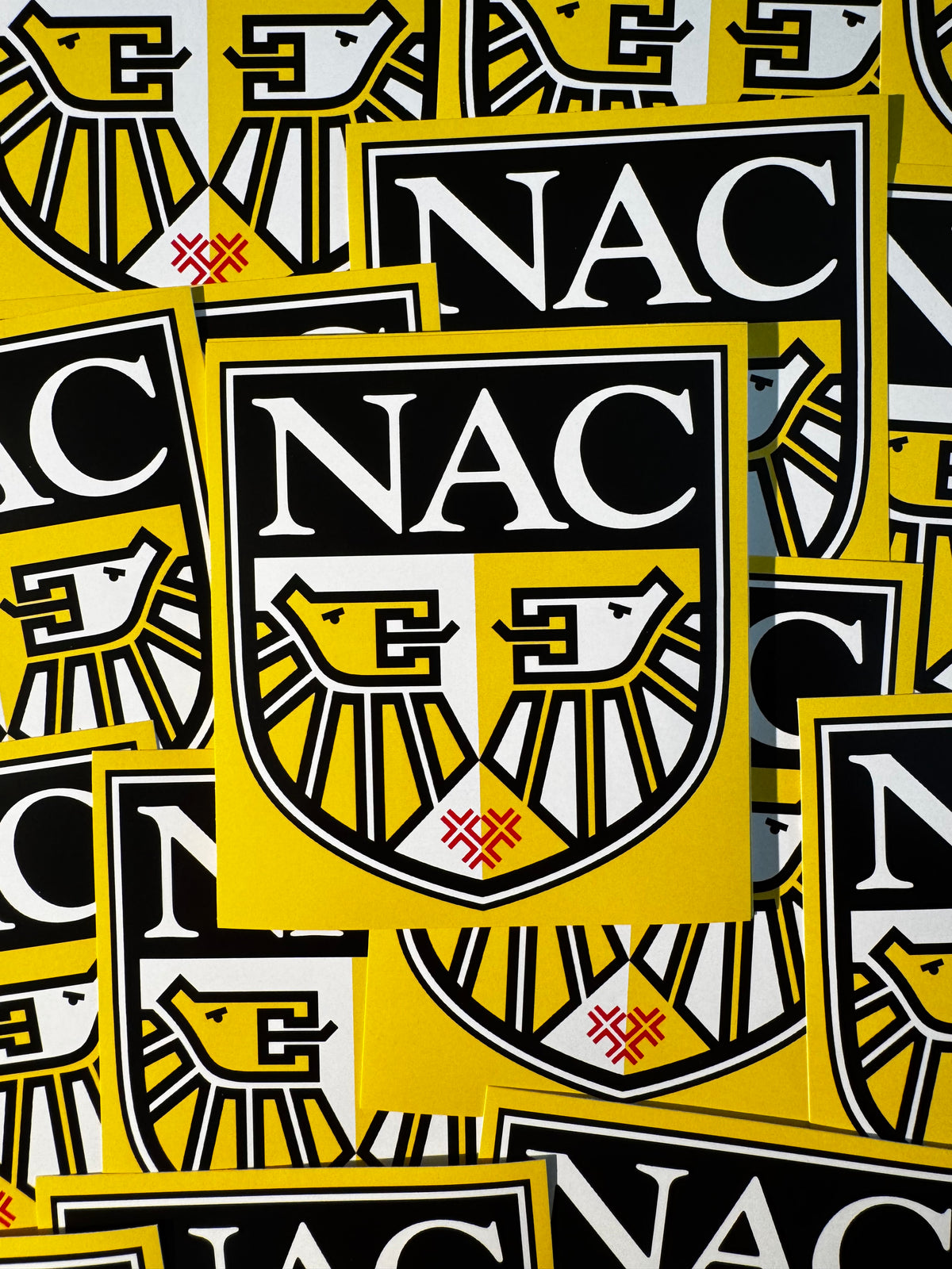 Stapel gele NAC stickers met het oude clublogo van 1996 tot 2012