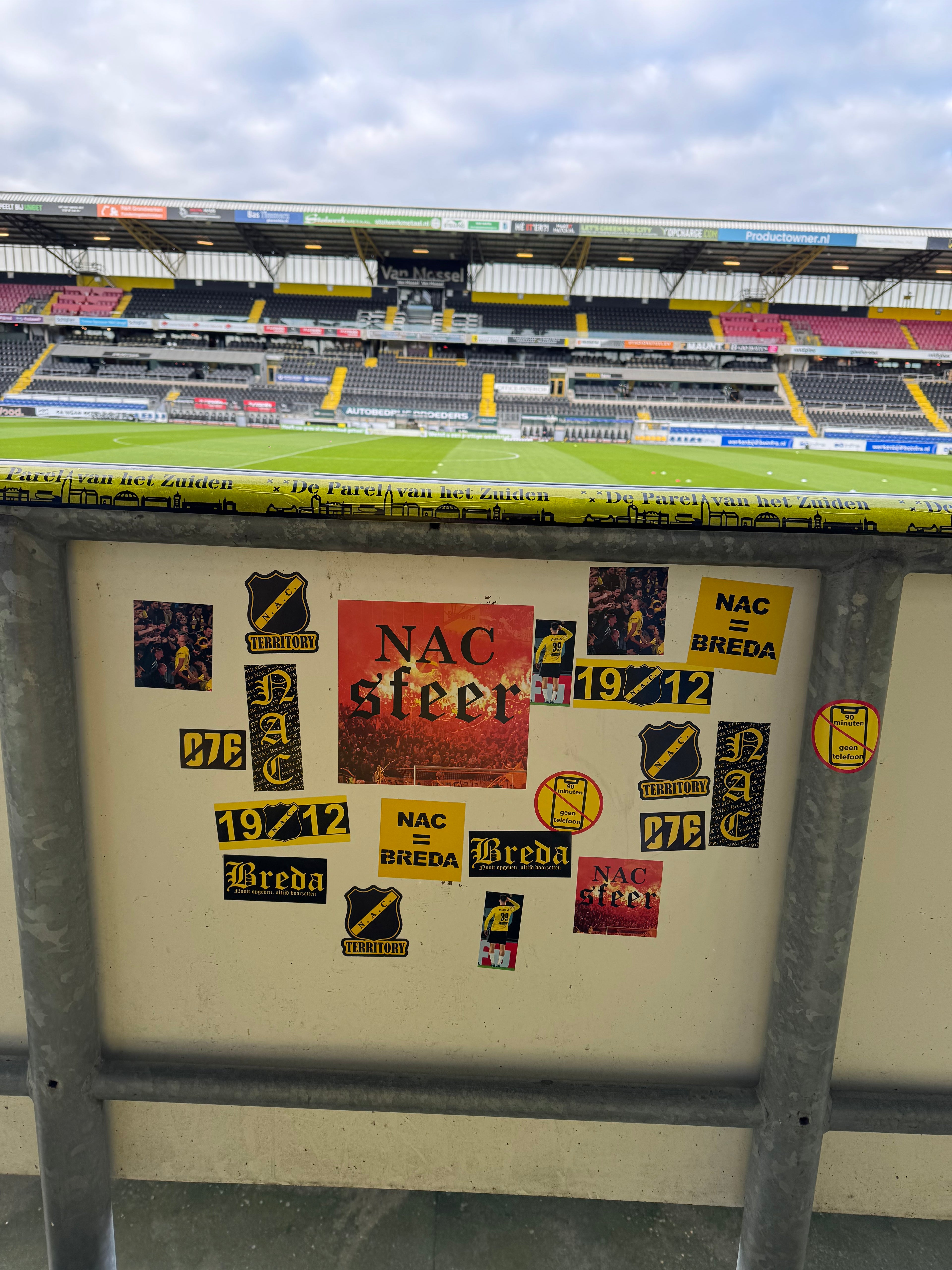 een grote collectie nacsfeer stickers en tape op de boarding geplakt in het nac stadion